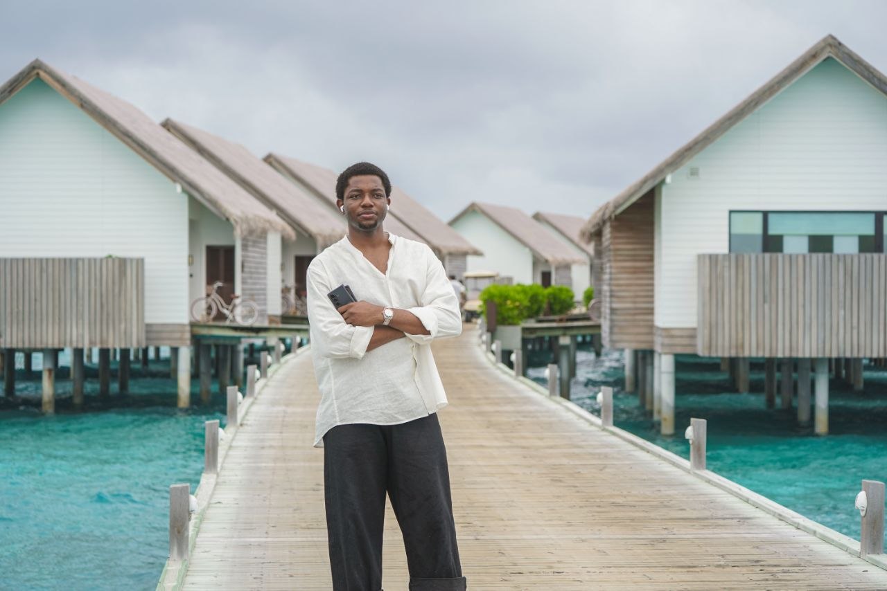 The person behind DXLDOJO standing on a waterfront boardwalk